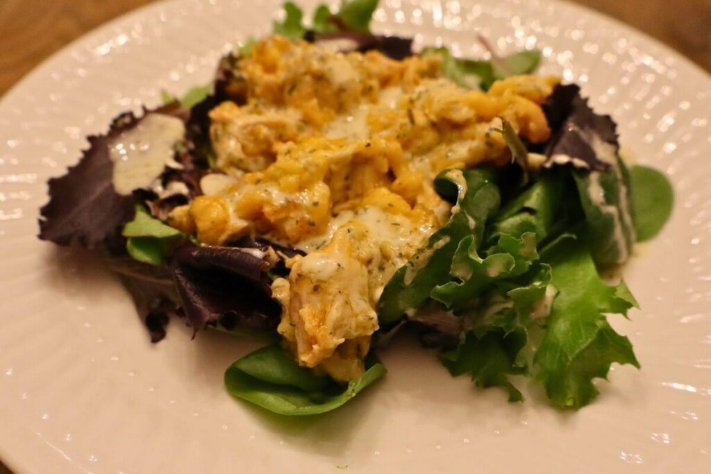plate with creamy buffalo chicken served on a bed of salad