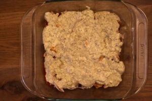 8x8 baking pan with uncooked buffalo chicken dip covered with ranch dressing