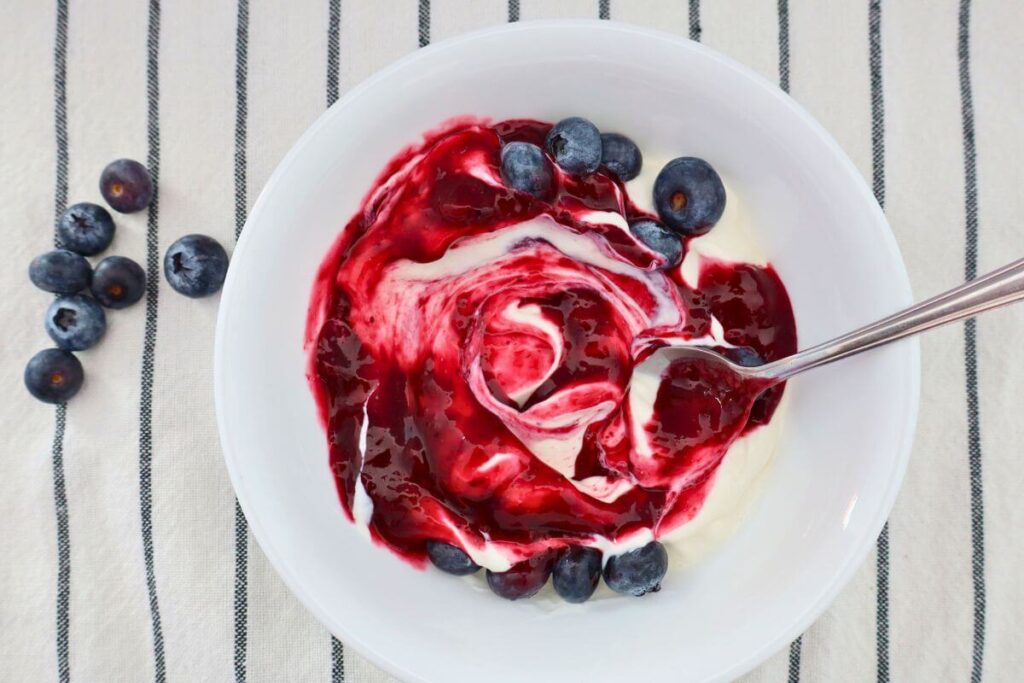 berry compote swirled into yogurt with fresh blueberries