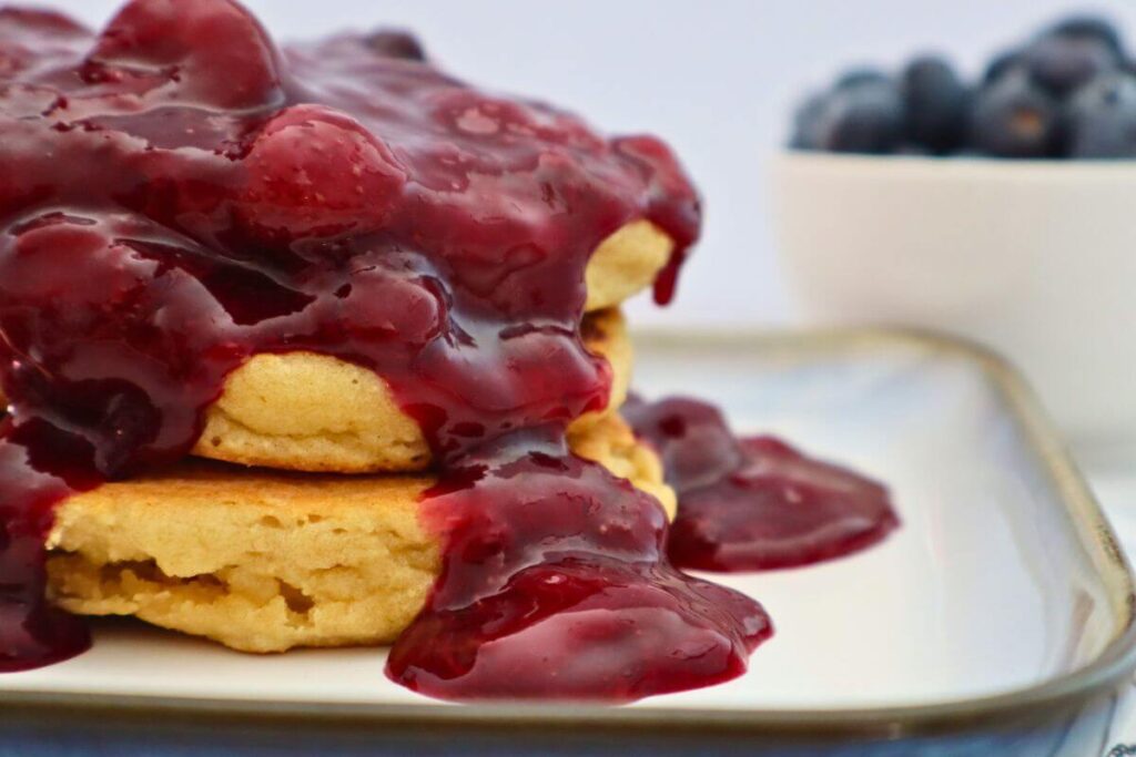 closeup of berry sauce drizzled over pancakes