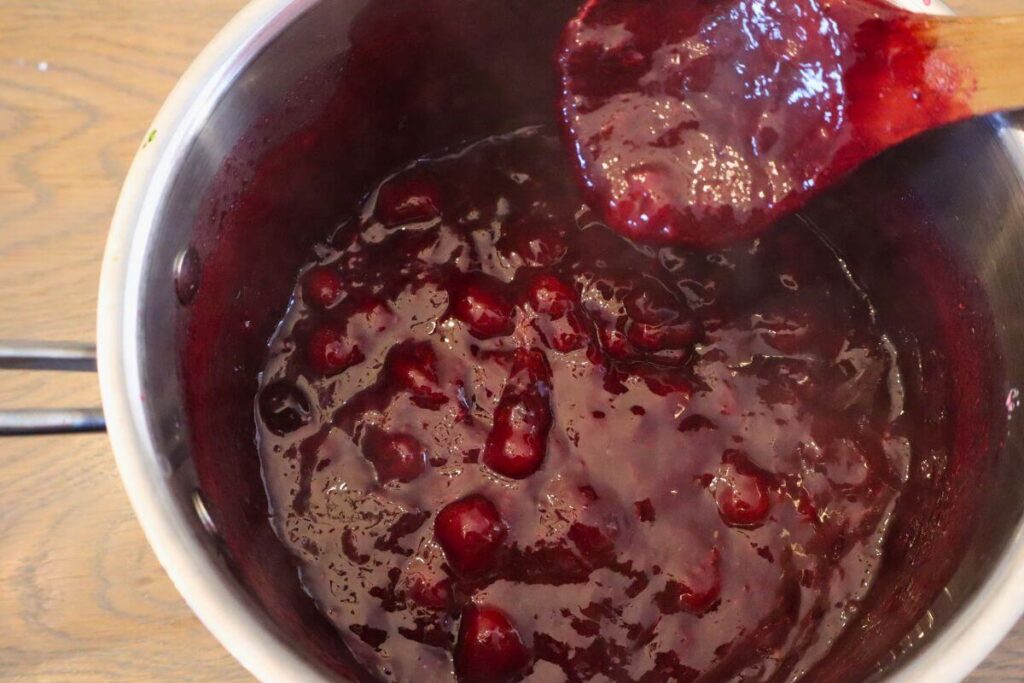 berry sauce in a kettle with wooden spoon