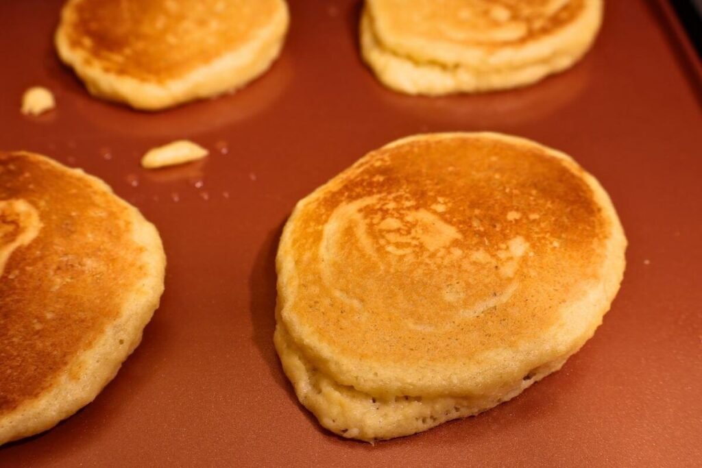 four fluffy almond flour pancakes on a griddle