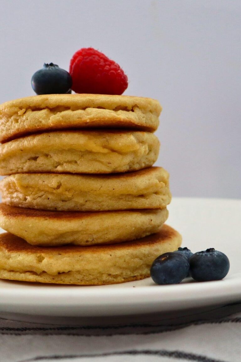 Stack of fluffy almond flour griddle pancakes with raspberries and blueberries sitting on a plate