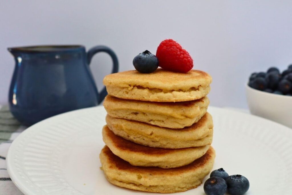 stack of 5 almond flour pancakes with raspberries and blueberries sitting on a plate