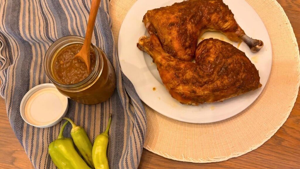 Homemade Gluten-Free Sweet Banana Pepper Honey Mustard Sauce (No Flour Needed) 1 jar of sweet banana pepper honey mustard sauce in a jar with a spoon sitting beside whole banana peppers and baked chicken covered in sauce