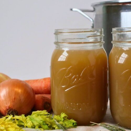 2 jars of finished beef bone broth with vegetables and a stockpot