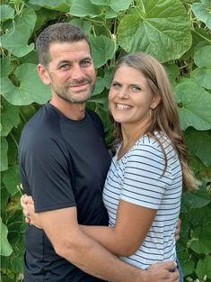 man and woman hugging in front of green vines