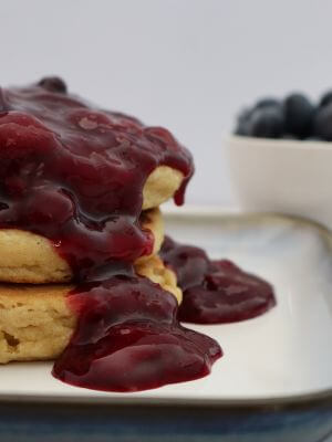 stack of 3 pancakes drizzled with berry sauce