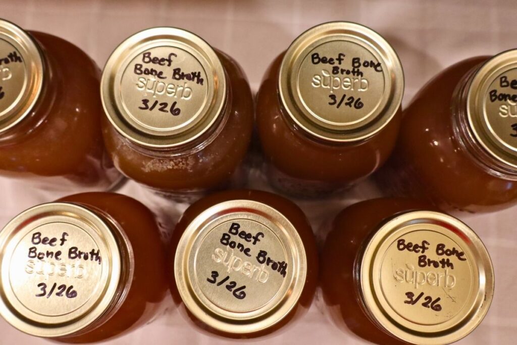 7 labeled jars of bone broth sitting on the counter.