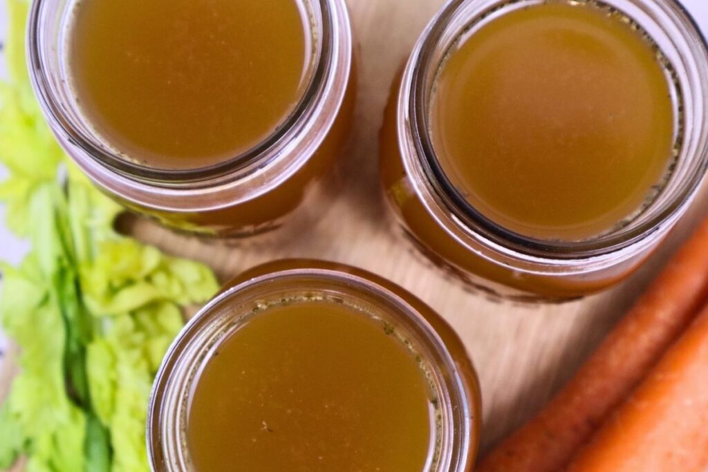 3 mason jars full of chicken bone broth with carrots and celery