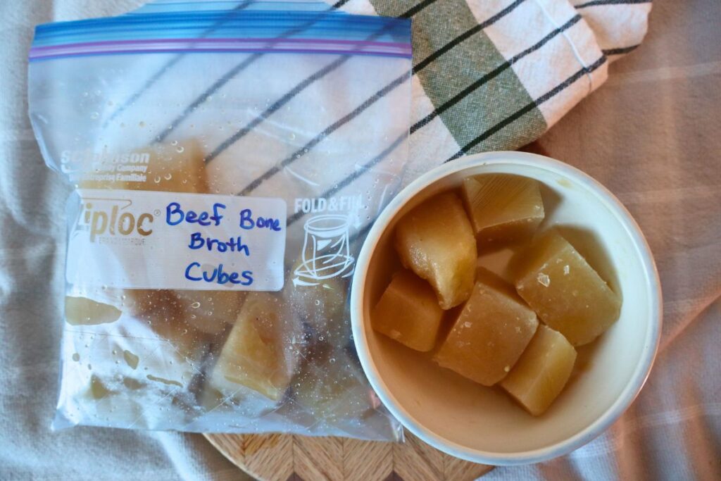Cubes of frozen bone broth in a bowl an in a freezer bag. Perfect portion size for adding to recipes, sauces, or for sipping.