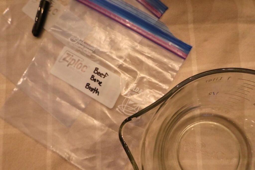 Labeled Ziplock bag for bone broth next to a Pyrex measuring bowl.