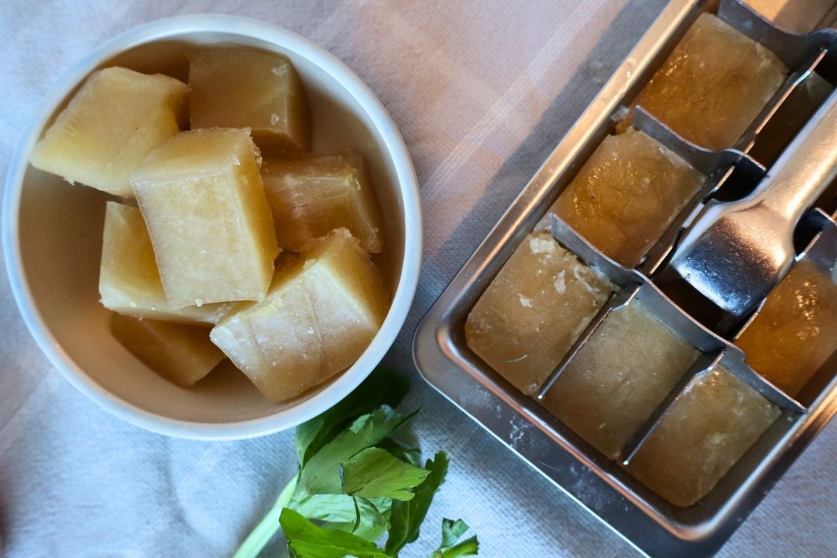 Small cubes of frozen bone broth from an ice cube tray demonstrating portent control.
