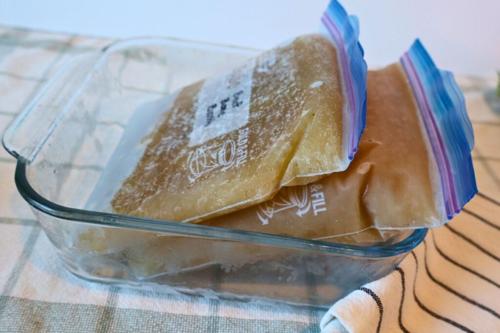 Two Ziplock bags of frozen beef bone broth in a Pyrex dish.