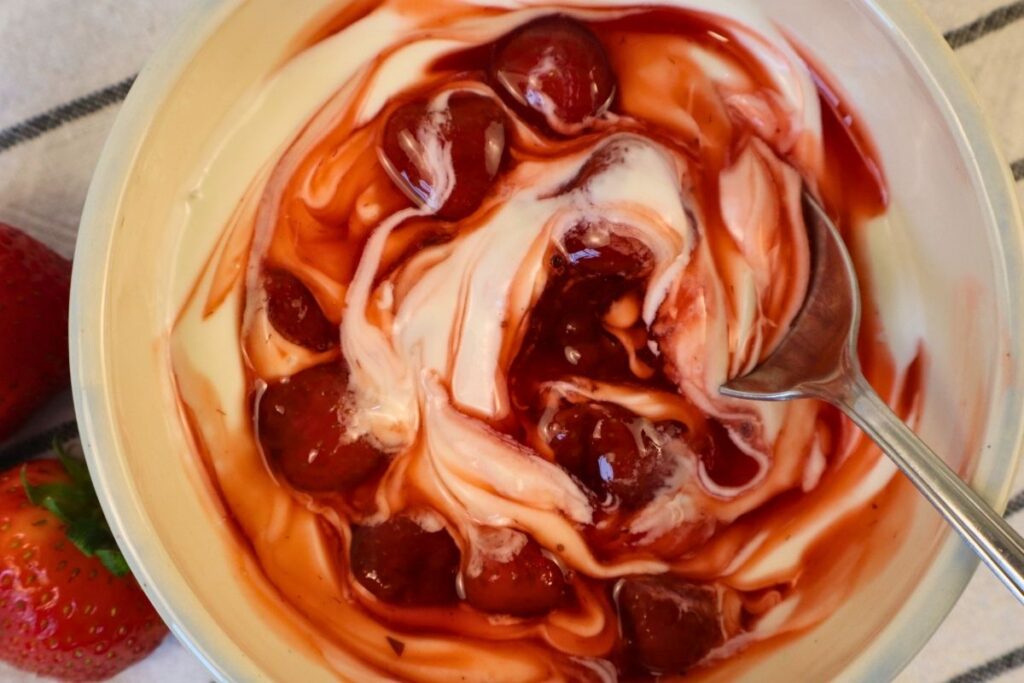 Closeup of healthy strawberry sauce served over yogurt with a spoon.