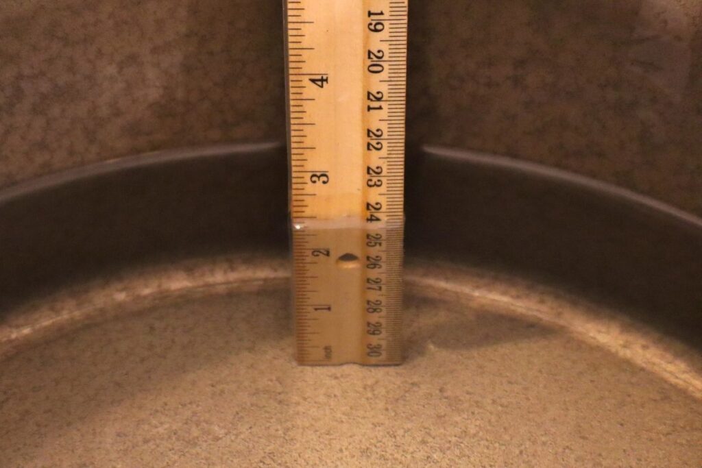 A ruler showing the correct water depth in a pressure canner.