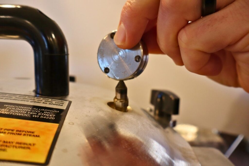 Placing the weight on the lid of a pressure canner.