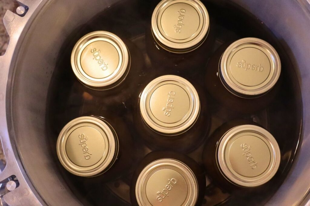 7 jars of pressure canned bone broth sitting in a pressure canner.