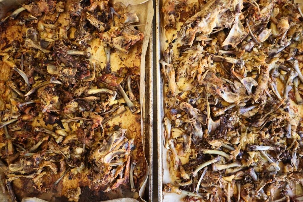 roasted chicken bones on baking trays covered with parchment paper