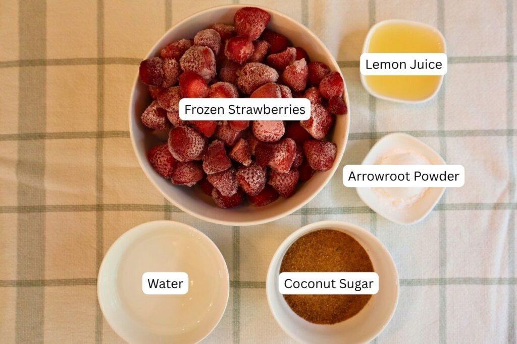 Simple strawberry sauce ingredients arranged on a white surface.