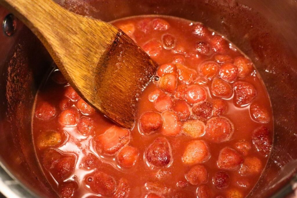 Strawberry sauce simmering in a pot on the stove.