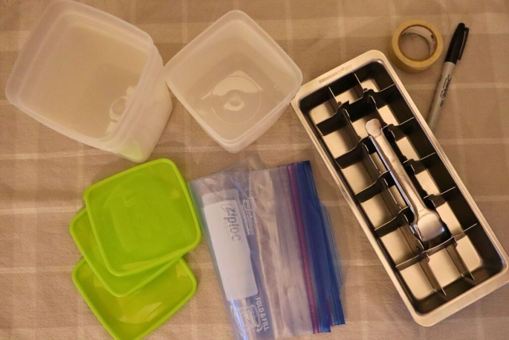Empty freezer containers, Ziplock bags, and ice cube tray used for freezing bone broth. Tape and Sharpe for recording the date on containers.