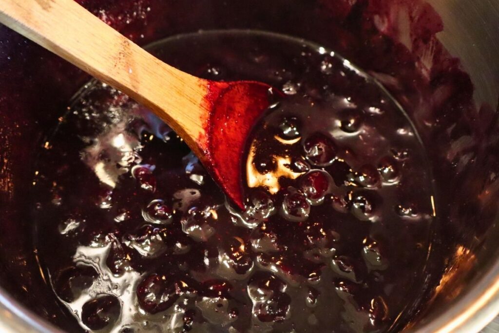 Blueberry sauce in a kettle after thickening with arrowroot, glossy and ready to serve.
