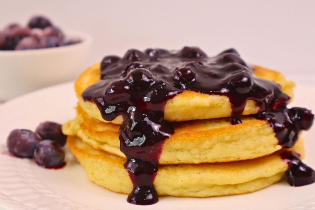 Blueberry sauce running down the side of a stack of pancakes.