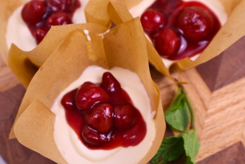 Mini cheesecake topped with homemade chunky strawberry sauce and fresh mint leaves