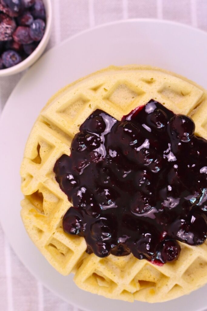 Overhead shot of waffles topped with blueberry sauce — easy homemade blueberry sauce with frozen blueberries.