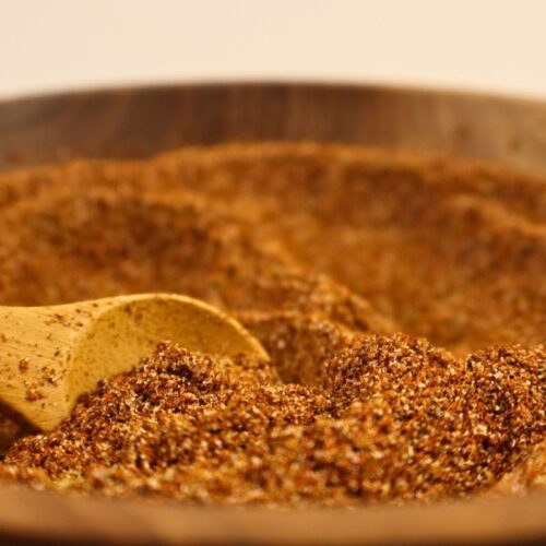 Closeup view of a bowl full of homemade taco seasoning with a wooden spoon.