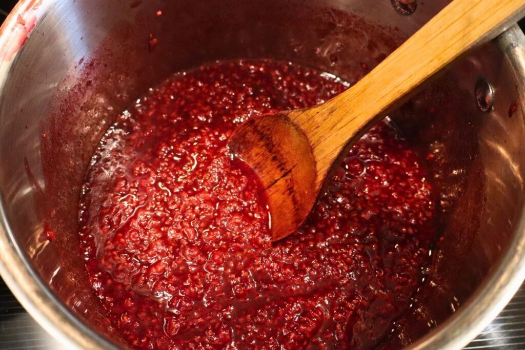 How to Make Raspberry Sauce with Frozen Raspberries 7 Freshly cooked raspberry sauce simmering in a kettle.