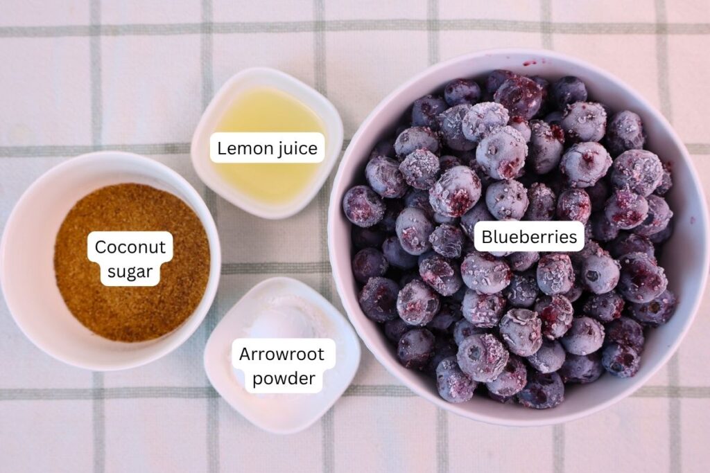 Ingredients laid out for making blueberry sauce, including frozen blueberries, coconut sugar, and lemon juice