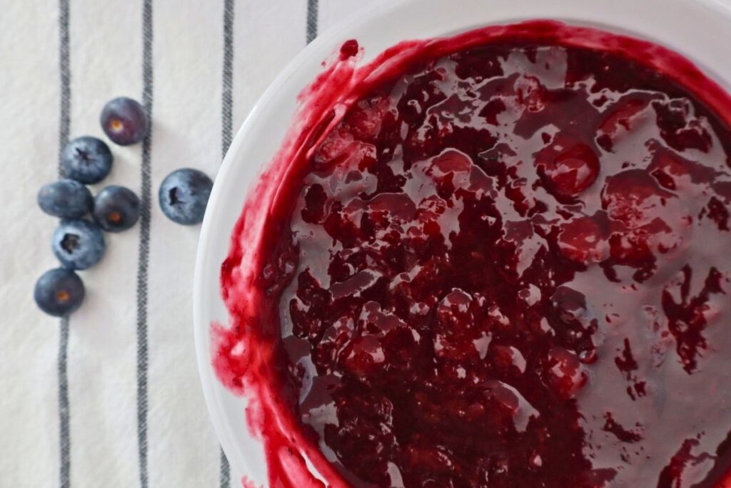Bowl of homemade mixed berry sauce with fresh blueberries on a white background