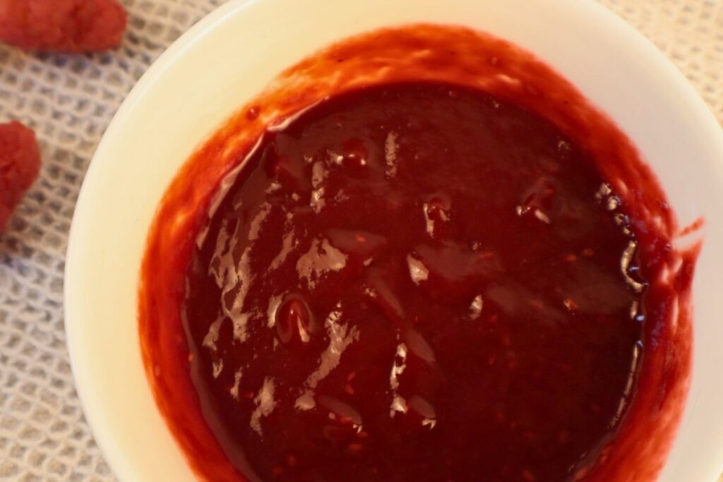How to Make Raspberry Sauce with Frozen Raspberries 11 Overhead view of smooth, strained raspberry sauce in a bowl.