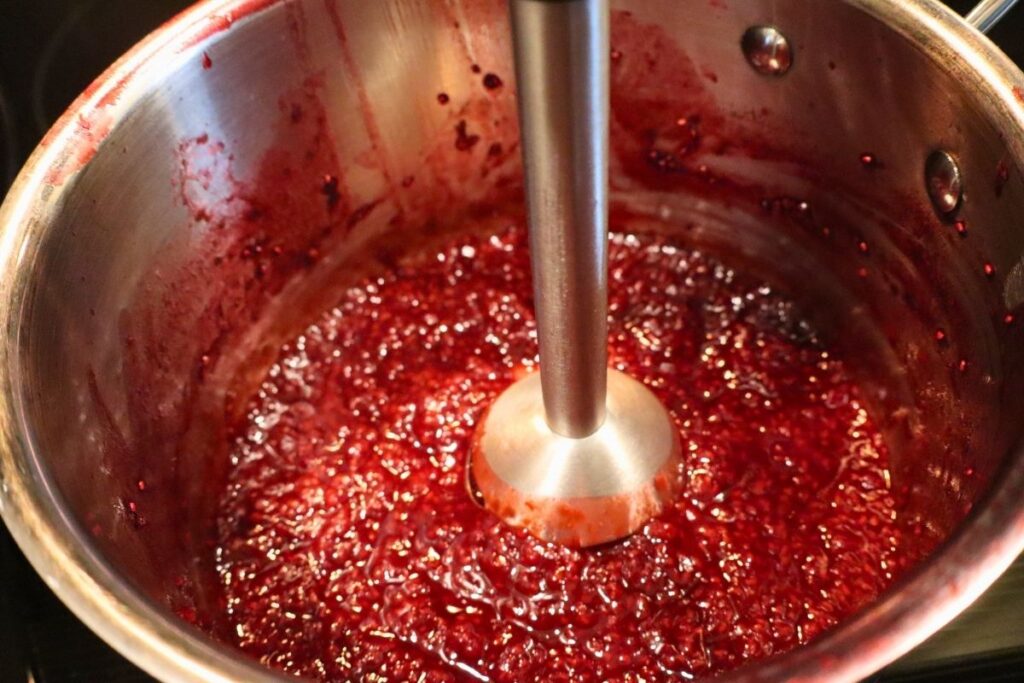 How to Make Raspberry Sauce with Frozen Raspberries 8 Using an immersion blender to purée raspberry sauce in the kettle.