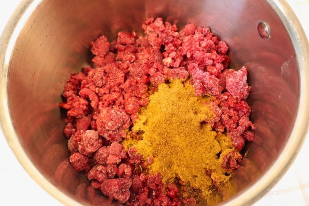 How to Make Raspberry Sauce with Frozen Raspberries 6 Overhead view of raspberry sauce ingredients combined in a bowl.