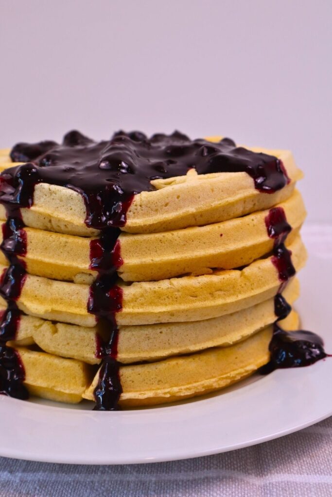 Stack of homemade waffles with blueberry sauce running down the sides — easy breakfast recipe idea