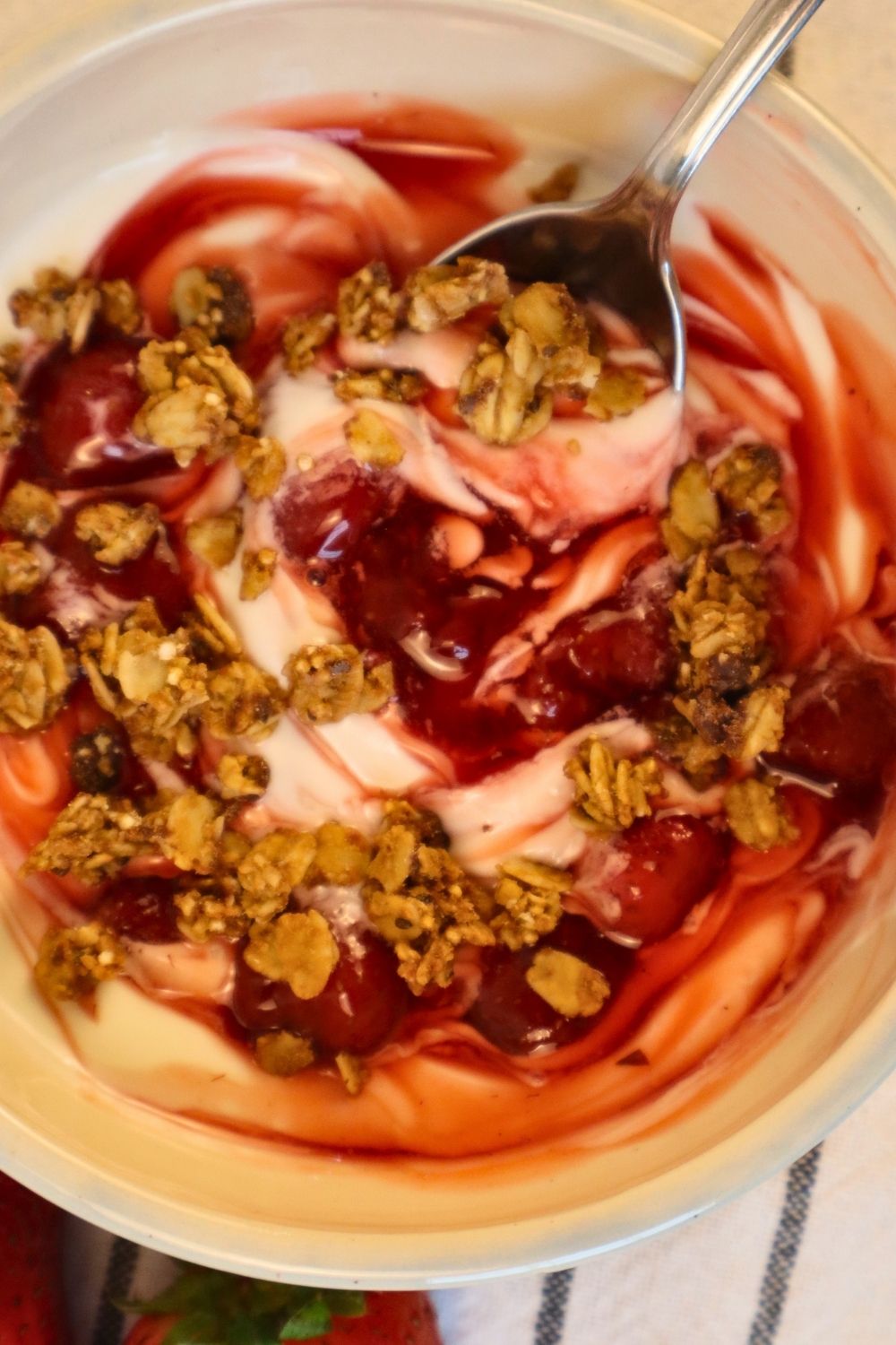 Homemade strawberry sauce swirled into creamy yogurt with crunchy granola — easy berry sauce recipe for a wholesome breakfast or snack