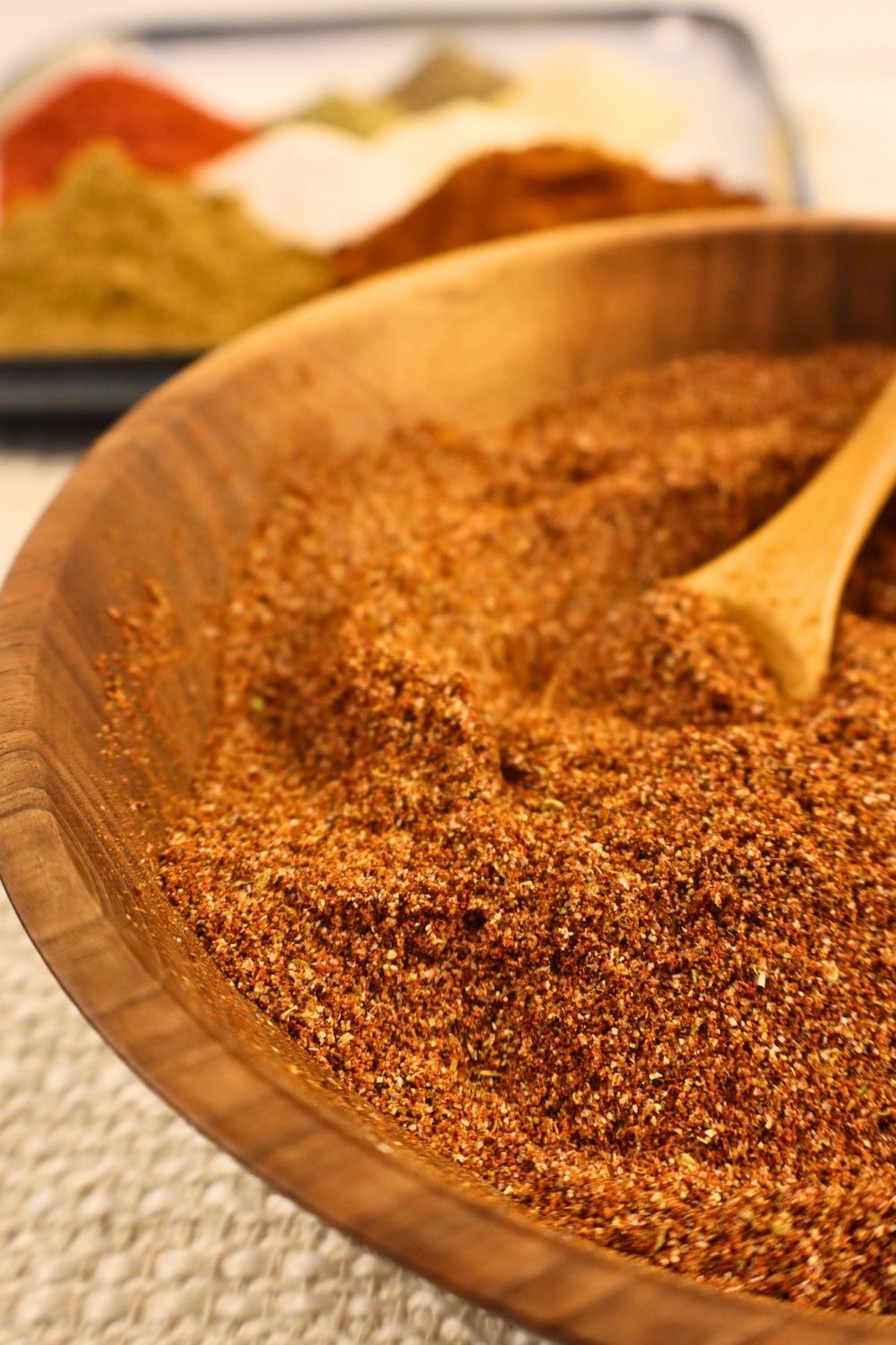 Bowl of homemade taco seasoning with a wooden spoon in it — easy DIY taco seasoning mix.