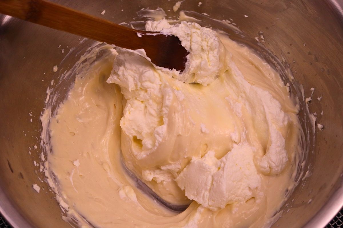 Gluten-Free Mini No-Bake Cheesecakes with Berry Sauce 14 Whipped cream being gently folded into the cream cheese mixture in a mixing bowl to make light and fluffy gluten free mini no bake cheesecake filling.