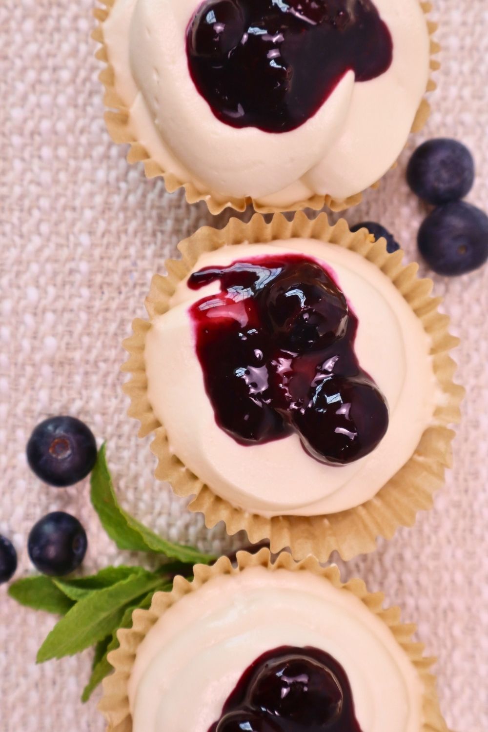 Gluten-Free Mini No-Bake Cheesecakes with Berry Sauce 2 Overhead view of gluten free mini no bake cheesecakes topped with homemade raspberry sauce, fresh raspberries, and mint — naturally sweetened, stunning, and so easy to make!