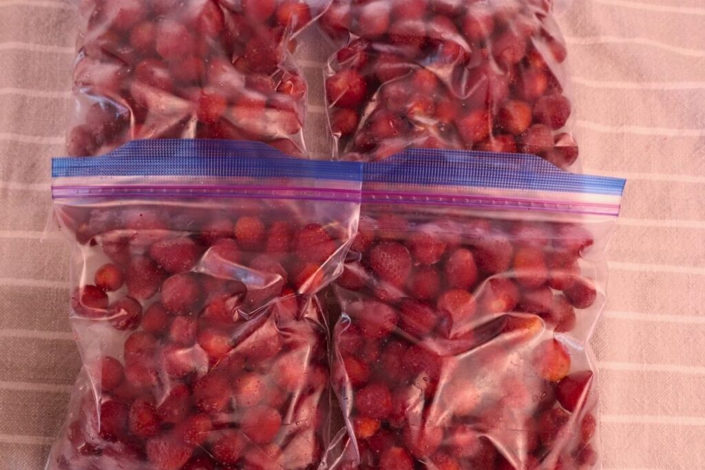 How to Freeze Strawberries (The Best Way to Preserve Fresh Berries) 12 Four freezer bags filled with frozen strawberries stacked together for freezer storage