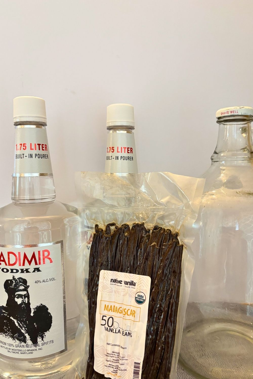 Large Batch Homemade Vanilla Extract Recipe with Vodka 6 Vanilla bean package, empty gallon jar, and two bottles of vodka for making large batch vanilla extract
