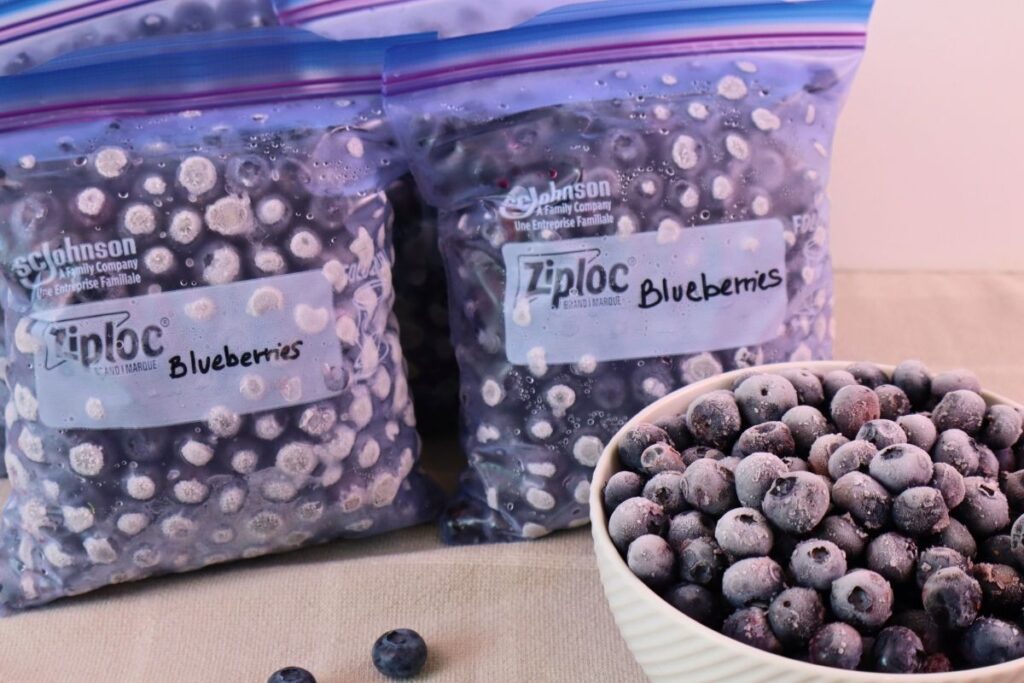 How to Freeze Fresh Blueberries for Year-Round Use 11 Two freezer bags of frozen blueberries standing beside a bowl of berries