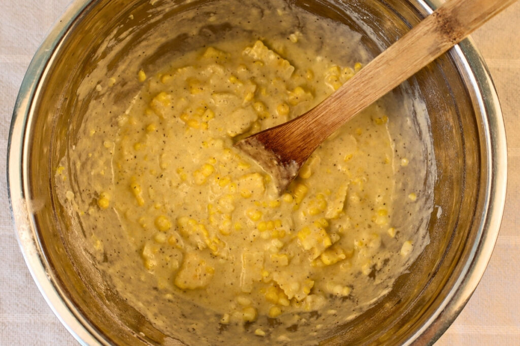 Gluten-Free Pennsylvania Dutch Corn Fritters 11 Gluten-free corn fritter batter stirred with a wooden spoon, with sweet corn kernels