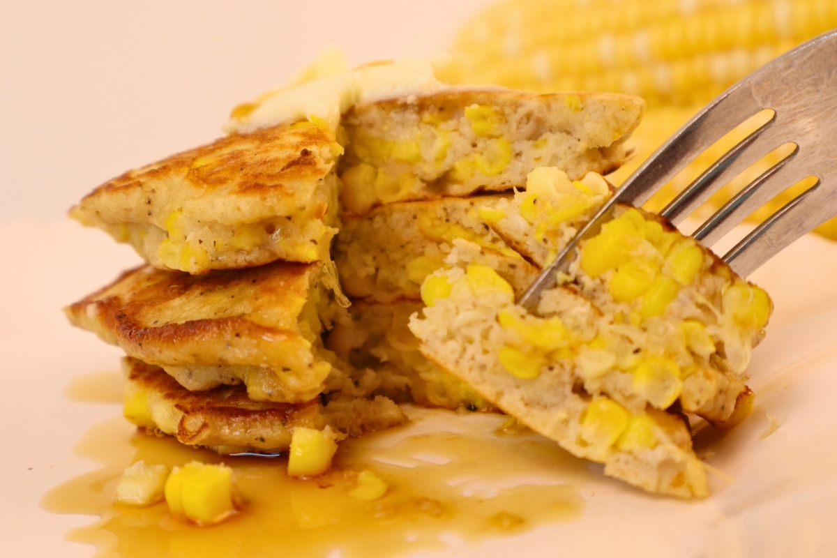 Maple syrup drizzled over a bite of gluten-free corn fritter on a fork