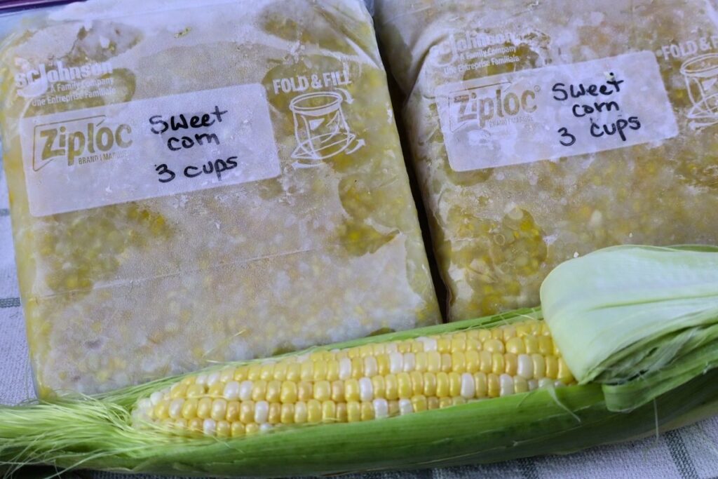 How to Freeze Sweet Corn: A Step-by-Step Preservation Guide 19 Bags of frozen sweet corn beside a single raw ear of corn.