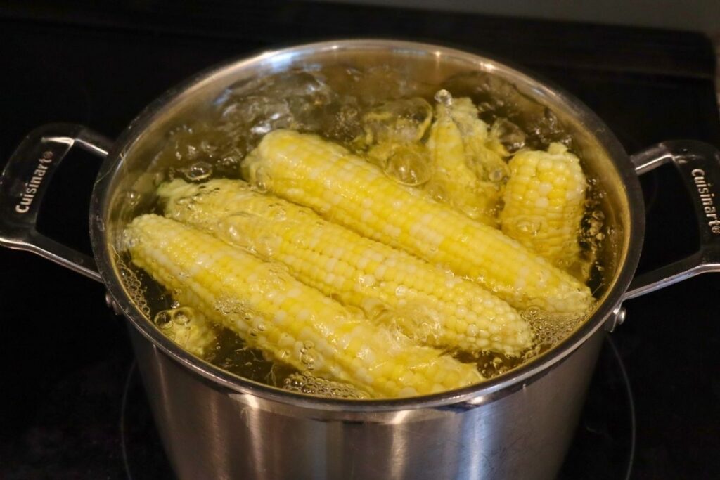 How to Freeze Sweet Corn: A Step-by-Step Preservation Guide 8 Whole ears of sweet corn blanching in a pot of boiling water