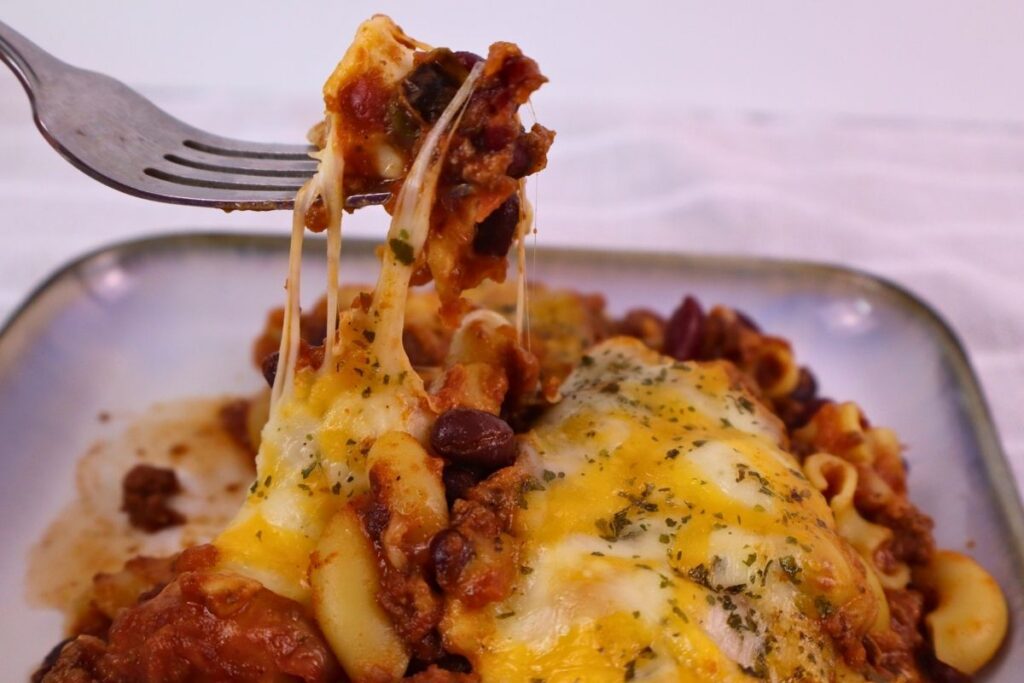 Easy Baked Gluten-Free Chili Mac 10 Fork lifting a cheesy bite of gluten-free chili mac from a plated serving